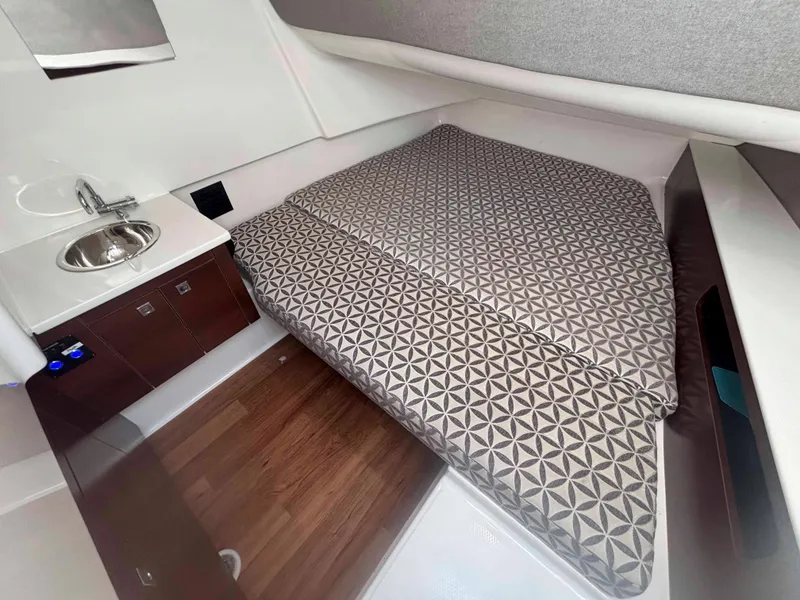 Slide: The Image of 2020 Chaparral 300 OSX cabin interior with patterned bedding and compact sink area. - 20