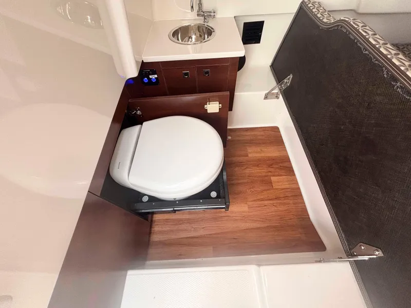 Slide: The Image of 2020 Chaparral 300 OSX boat bathroom with toilet, sink, and wood flooring. - 22