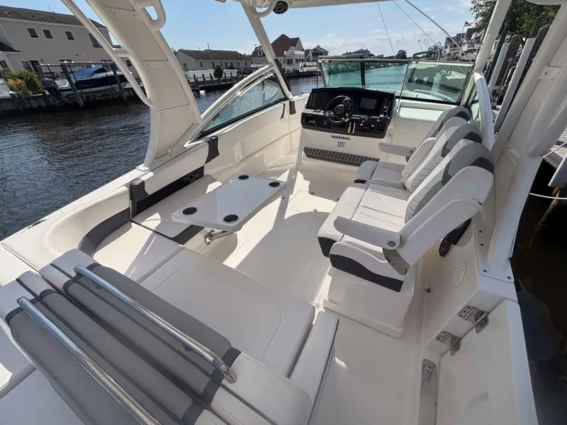 Slide: The Image of 2020 Chaparral 300 OSX boat interior with seating and helm, docked by waterfront homes. - 33