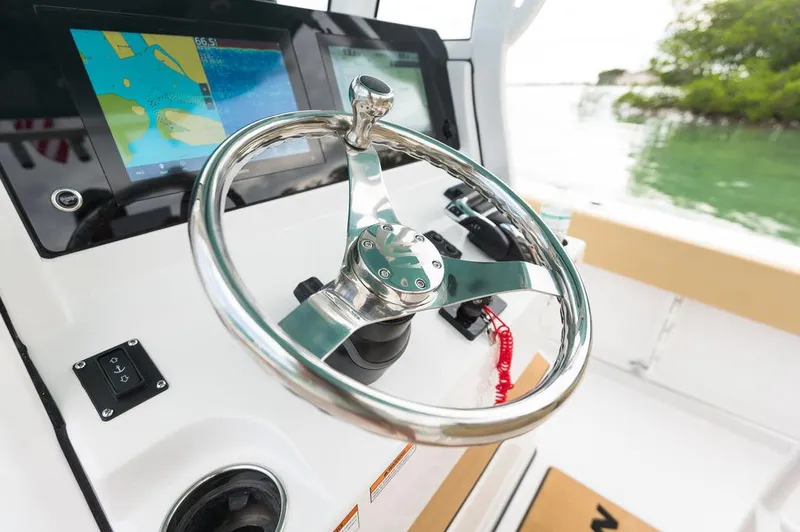 Slide: The Image of 2025 Sportsman Heritage 231 boat helm with modern navigation displays and chrome steering wheel. - 23