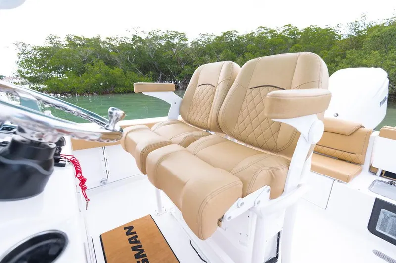 Slide: The Image of 2025 Sportsman Heritage 231 boat with tan leather seats and lush greenery background. - 25