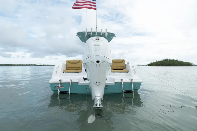 Slide: The Image of 2025 Sportsman Heritage 231 boat with American flag on calm water. - 9