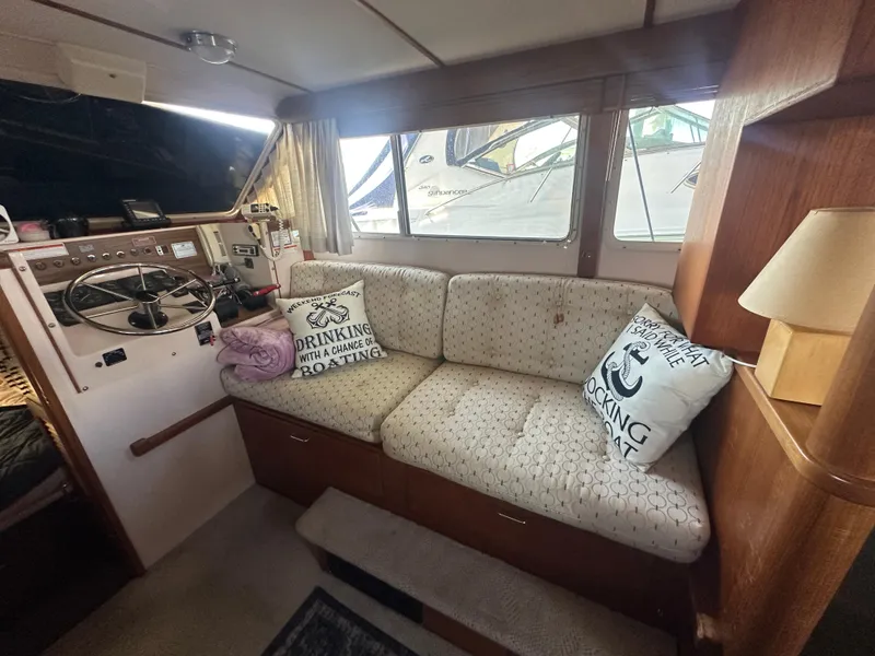 Slide: The Image of 1989 Tollycraft 30 Sedan interior with helm, cushioned seating, nautical-themed pillows, and lamp. - 13