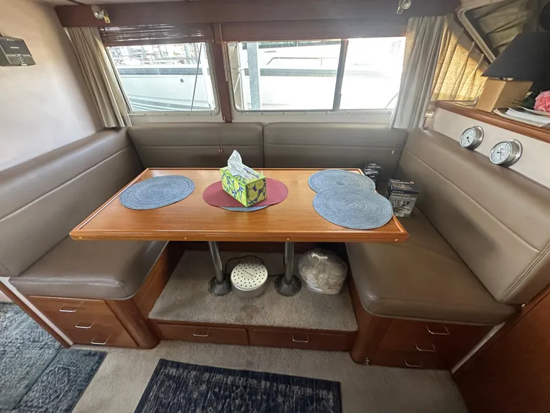 Slide: The Image of 1989 Tollycraft 30 Sedan interior with dining area, wooden table, and cushioned seating. - 17