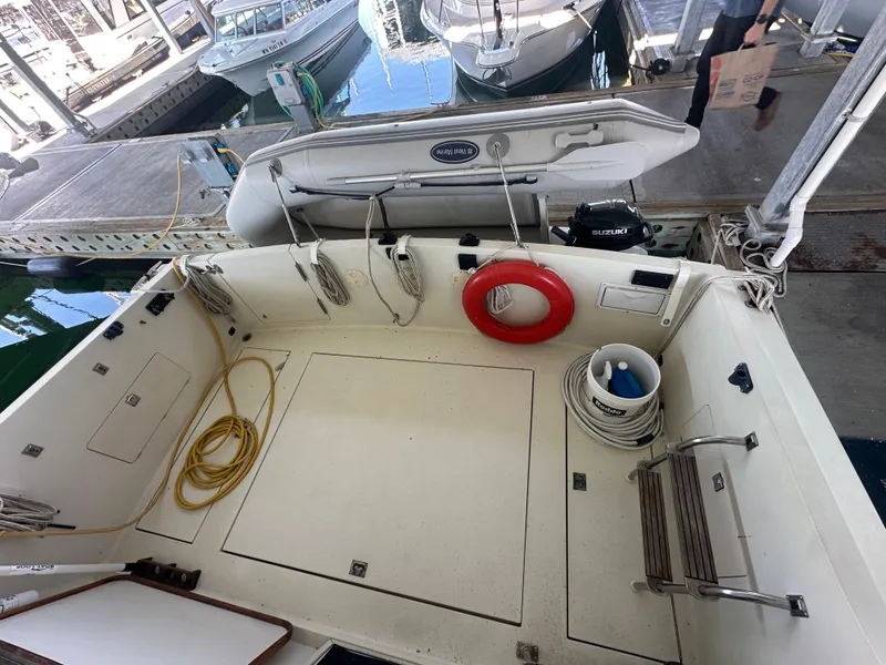 Slide: The Image of 1989 Tollycraft 30 Sedan boat deck with lifebuoy, ropes, and docked inflatable boat. - 5