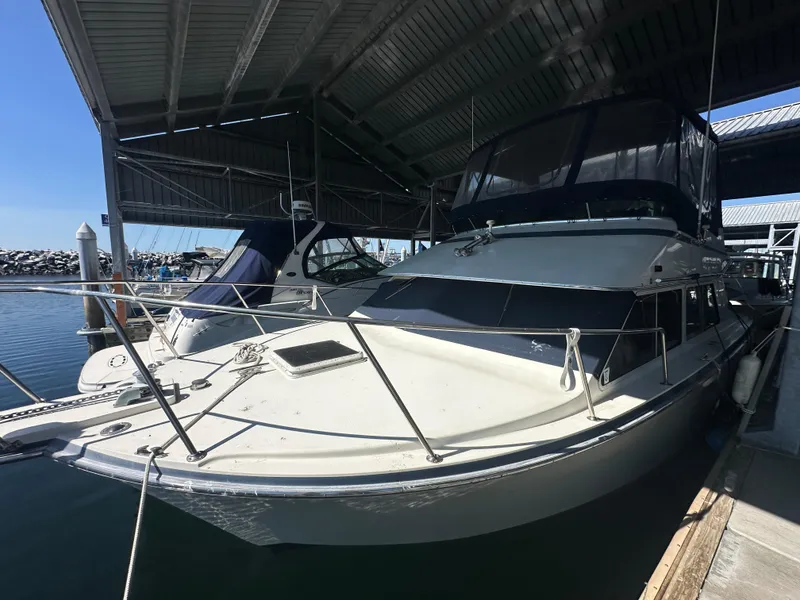 Slide: The Image of 1989 Tollycraft 30 Sedan boat docked under a covered marina. - 6