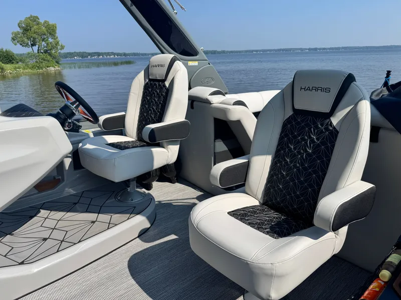 Slide: The Image of 2024 Harris 250 Grand Mariner boat interior with luxurious seating on a serene lake. - 10