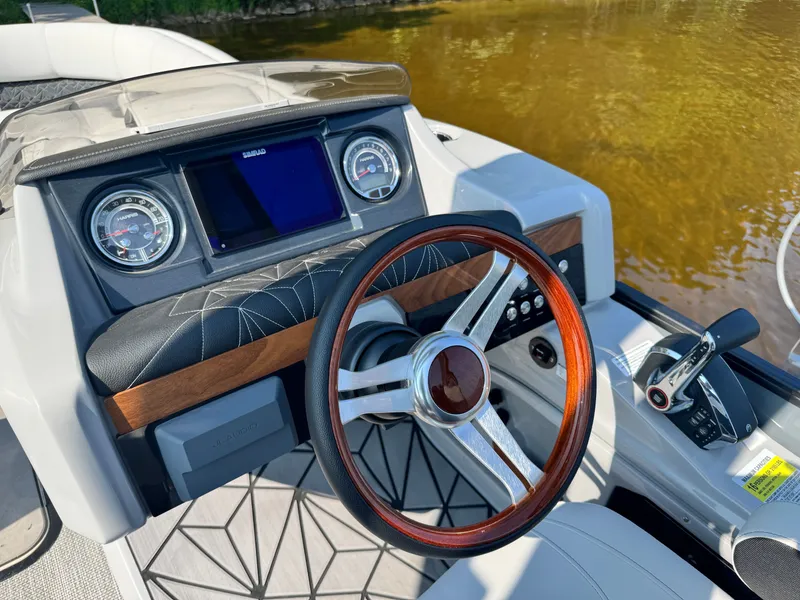 Slide: The Image of 2024 Harris 250 Grand Mariner boat dashboard with wooden steering wheel and modern controls. - 13