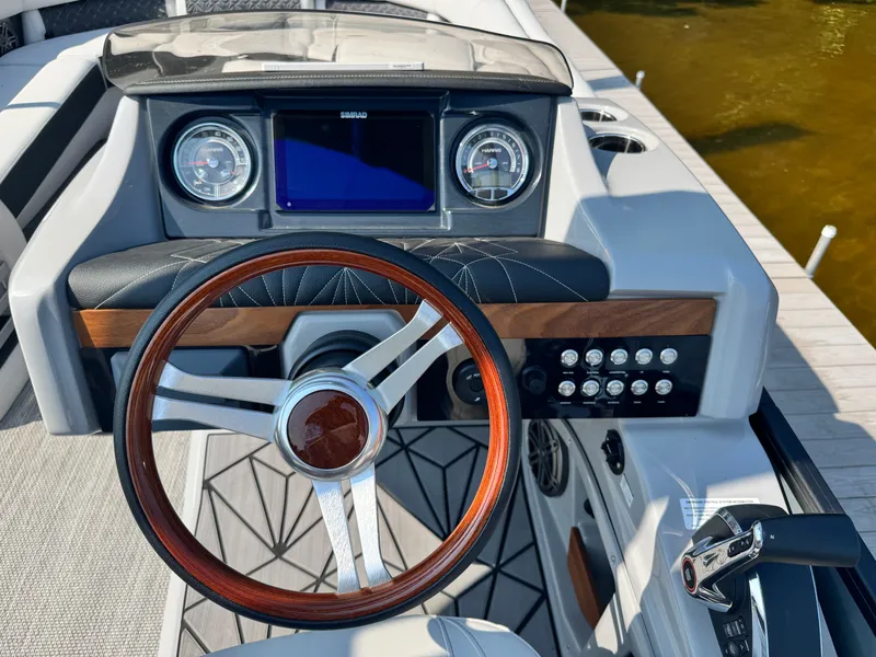 Slide: The Image of 2024 Harris 250 Grand Mariner dashboard with wooden steering wheel and modern controls. - 14
