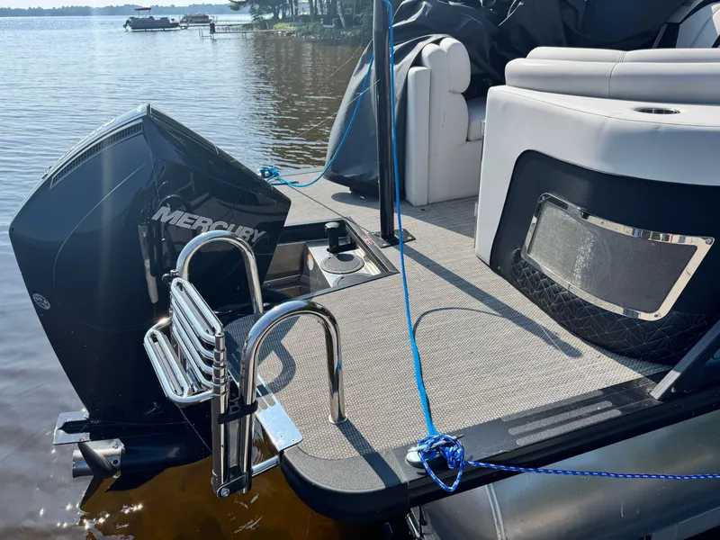 Slide: The Image of 2024 Harris 250 Grand Mariner boat with Mercury engine, docked on a sunny day. - 18