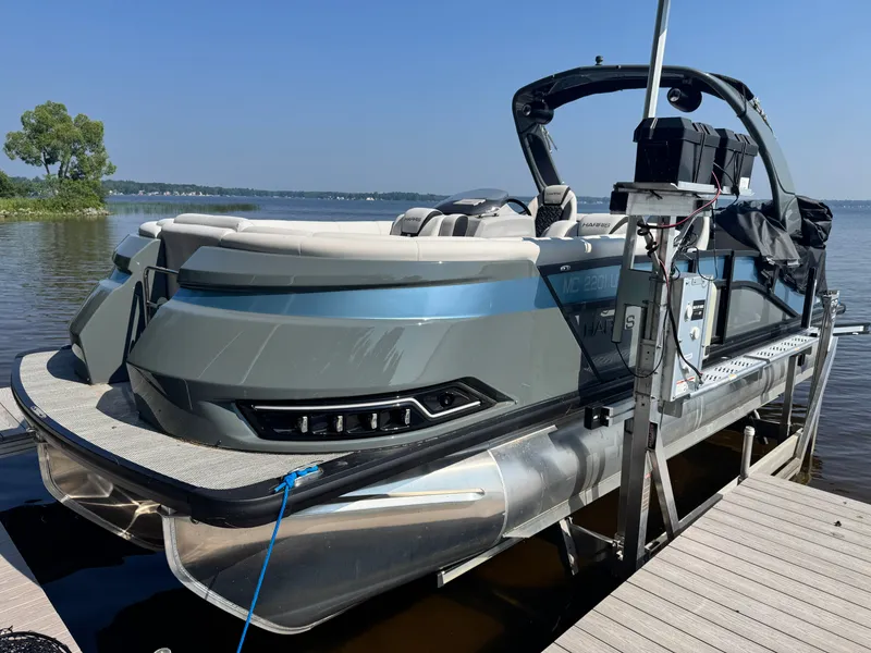 Slide: The Image of 2024 Harris 250 Grand Mariner pontoon boat docked on a sunny day. - 2