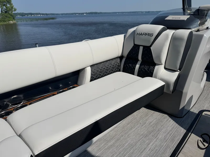 Slide: The Image of 2024 Harris 250 Grand Mariner boat interior with luxurious seating by the water. - 6