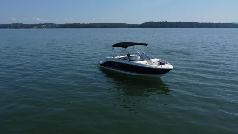 Slide: The Image of 2017 Sea Ray SLX 230 boat cruising on a calm lake under a clear sky. - 10