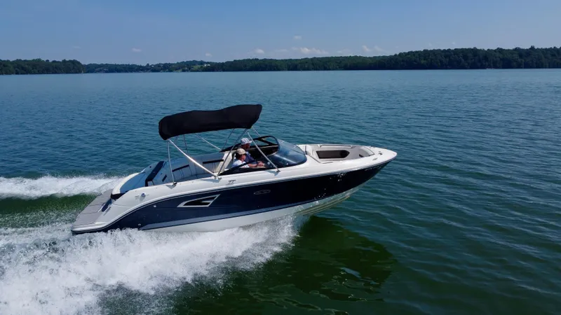 Slide: The Image of 2017 Sea Ray SLX 230 boat cruising on a serene lake under a clear blue sky. - 2
