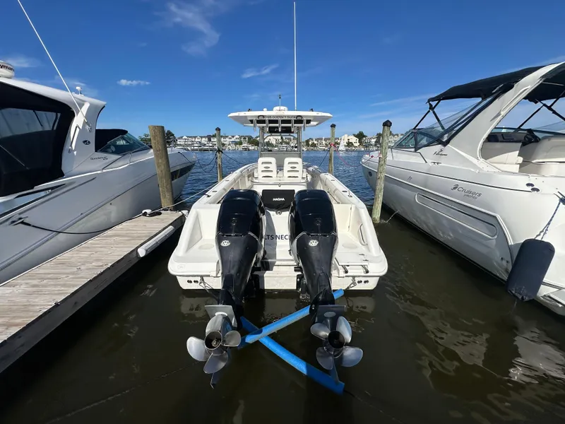 Slide: The Image of 2005 Boston Whaler 320 Outrage docked between two boats, featuring dual outboard engines. - 40