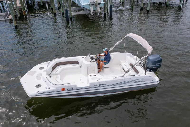 Slide: The Image of 2013 Hurricane SunDeck Sport 201 OB boat on water, with a person steering. - 0