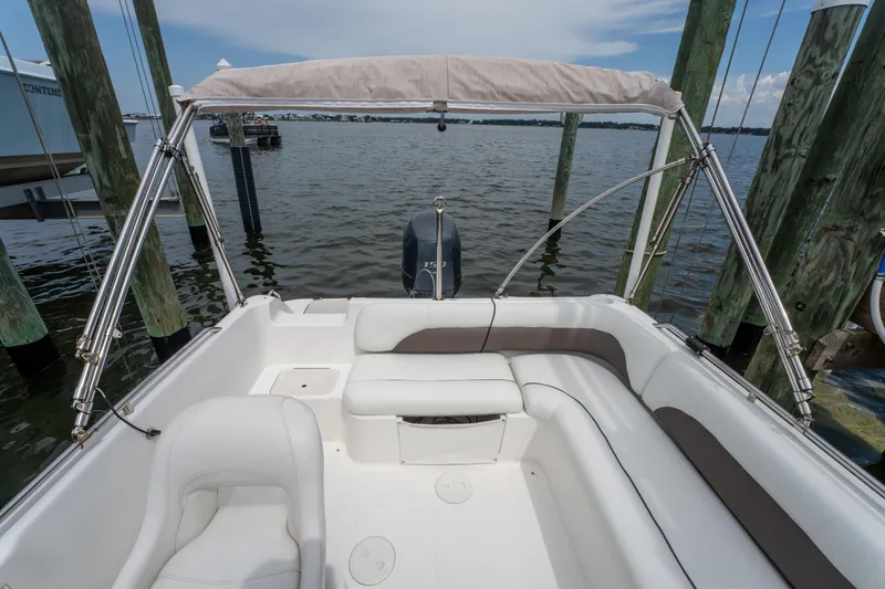 Slide: The Image of 2013 Hurricane SunDeck Sport 201 OB boat interior with seating and canopy, docked by wooden posts. - 19