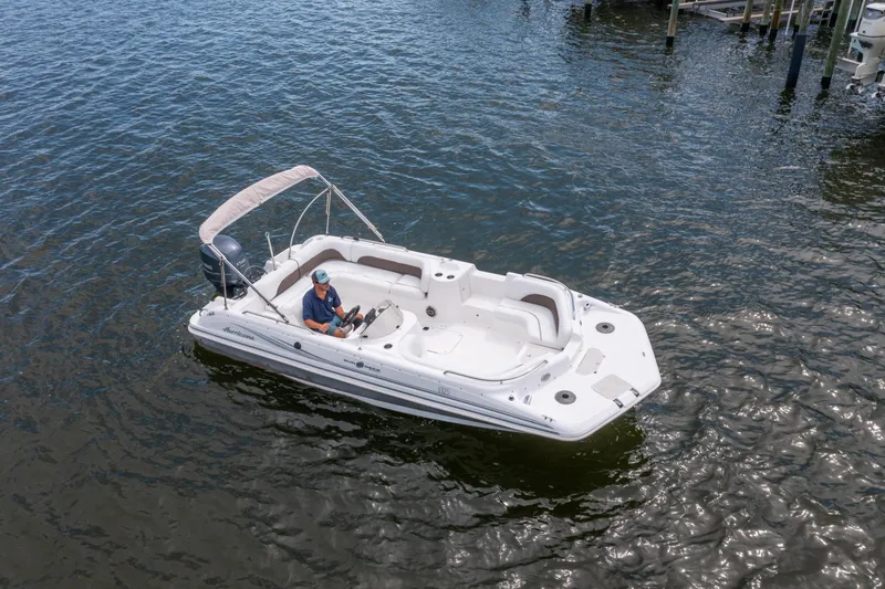 Slide: The Image of 2013 Hurricane SunDeck Sport 201 OB boat on water, featuring a person at the helm. - 25