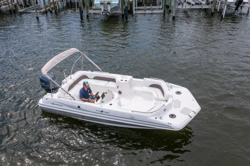 Slide: The Image of 2013 Hurricane SunDeck Sport 201 OB boat on water, with a person at the helm. - 26