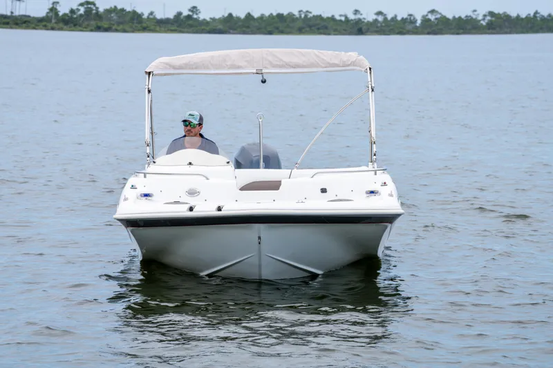 Slide: The Image of 2013 Hurricane SunDeck Sport 201 OB boat on calm water, with canopy and driver. - 4