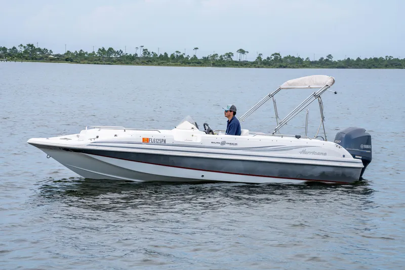 Slide: The Image of 2013 Hurricane SunDeck Sport 201 OB boat on calm water with a person at the helm. - 8
