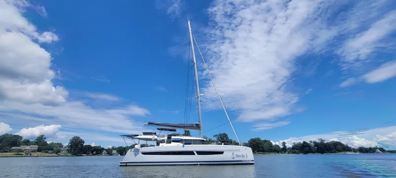 Slide: The Image of 2023 Fountaine Pajot Aura 51 catamaran sailing on a calm, scenic waterway. - 45