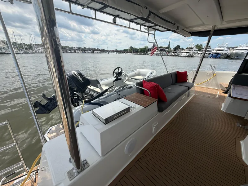 Slide: The Image of 2023 Fountaine Pajot Aura 51 yacht deck with seating, red cushions, and water view. - 5