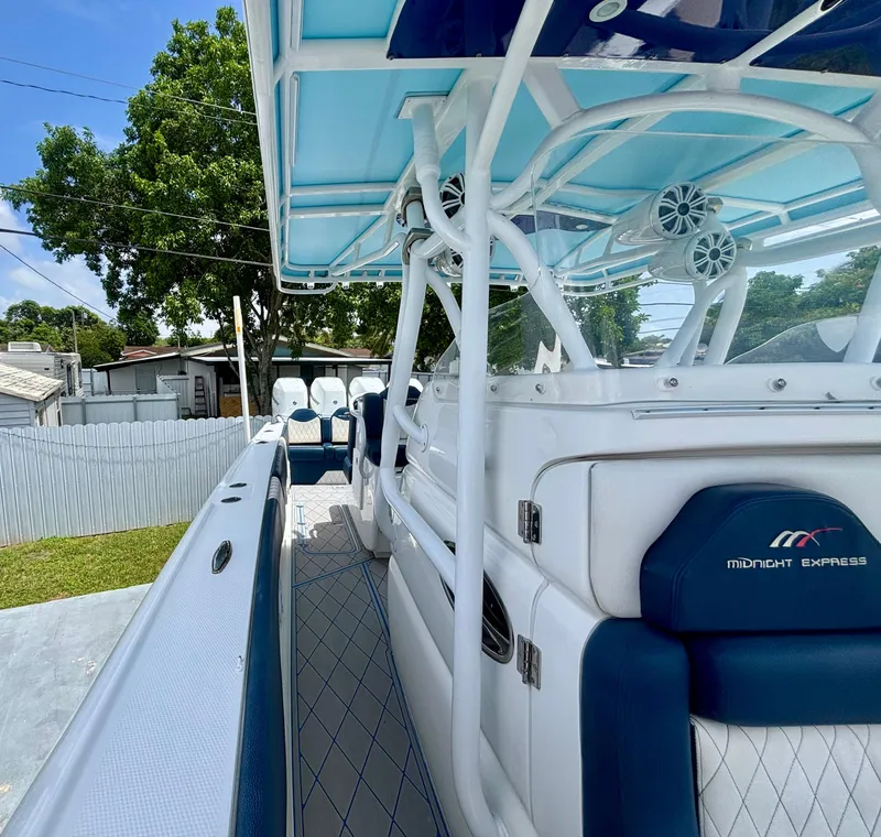 Slide: The Image of 2007 Midnight Express 39 Cuddy boat interior with blue and white seating, under a clear sky. - 14