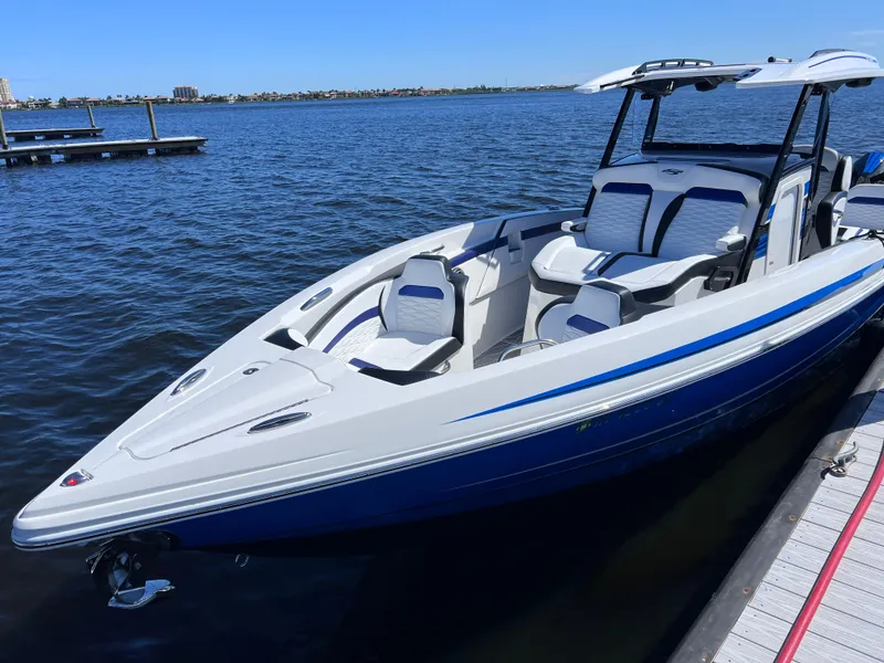 Slide: The Image of 2023 Sunsation 32 CCX boat docked on calm water, featuring sleek design and modern seating. - 21