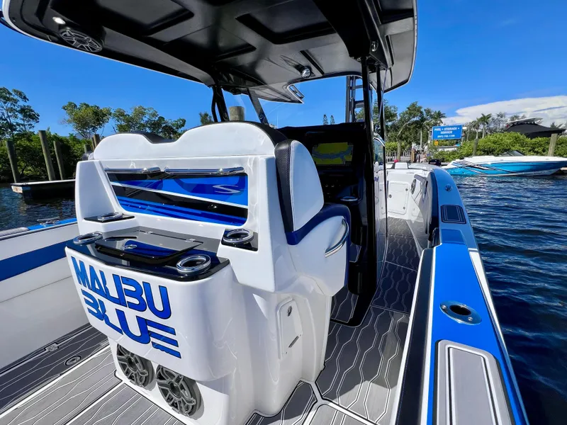 Slide: The Image of 2023 Sunsation 32 CCX boat with "Malibu Blue" branding, docked on a sunny day. - 32