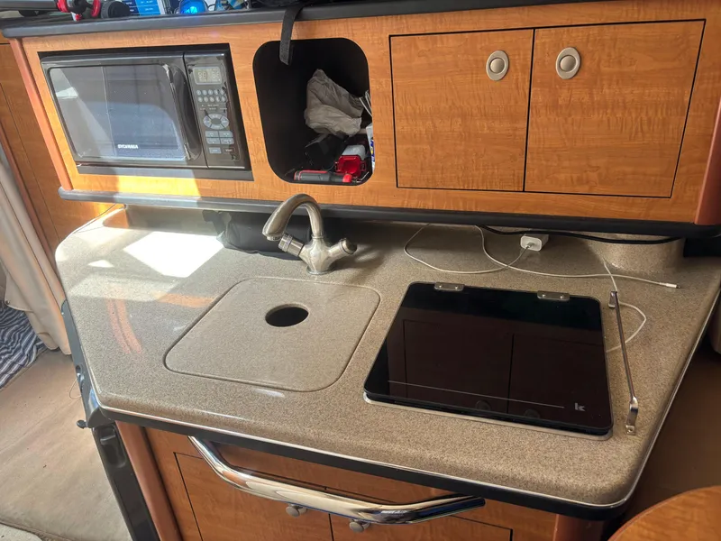 Slide: The Image of 2006 Sea Ray 260 Sundancer galley with sink, microwave, and storage cabinets. - 23