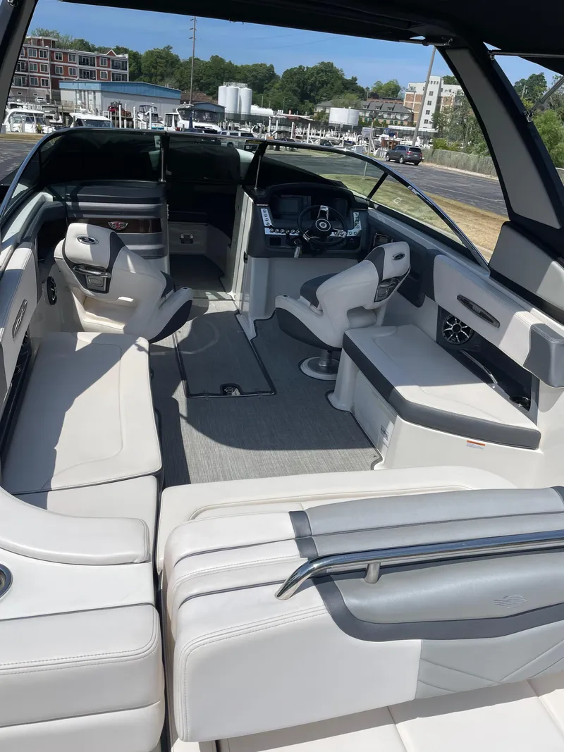 Slide: The Image of 2018 Chaparral 267 SSX boat interior with seating and helm, docked outdoors. - 14
