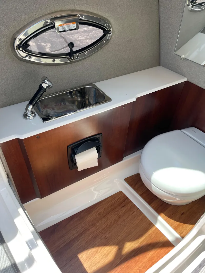 Slide: The Image of 2018 Chaparral 267 SSX boat bathroom with sink, toilet, and wood accents. - 17