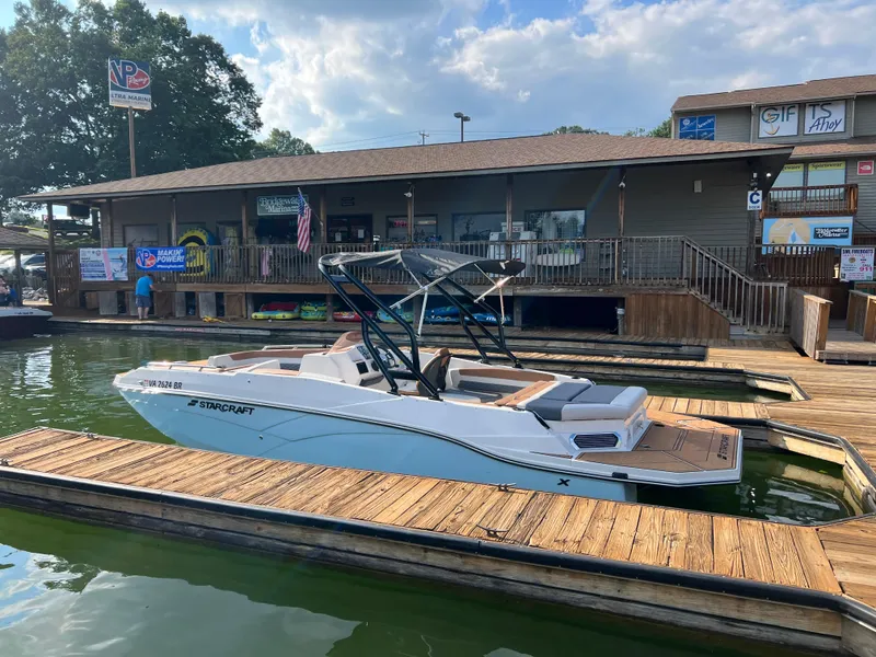Slide: The Image of 2025 Starcraft SVX 231 IO boat docked at a marina with a wooden deck. - 13