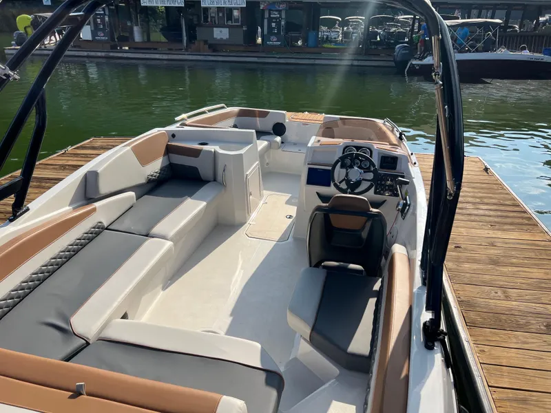 Slide: The Image of 2025 Starcraft SVX 231 IO boat interior with sleek seating and modern dashboard at a dock. - 3