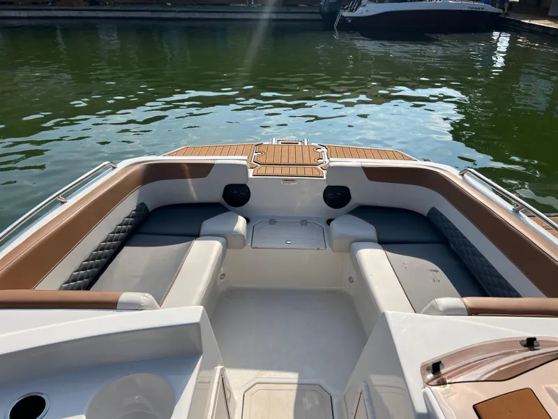 Slide: The Image of 2025 Starcraft SVX 231 IO boat interior with cushioned seating and wood accents on calm water. - 4