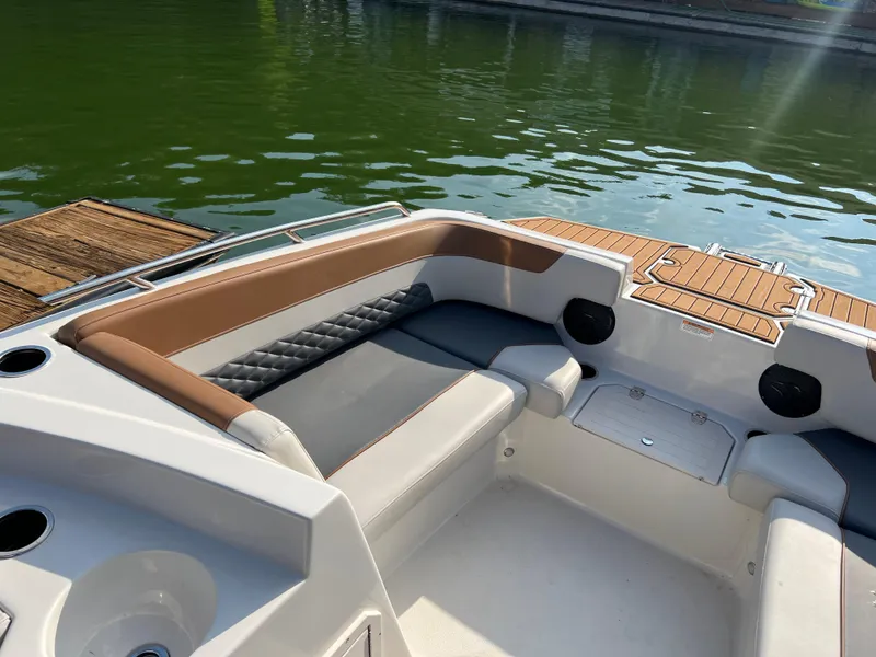 Slide: The Image of 2025 Starcraft SVX 231 IO boat interior with cushioned seating and wood accents by the water. - 6
