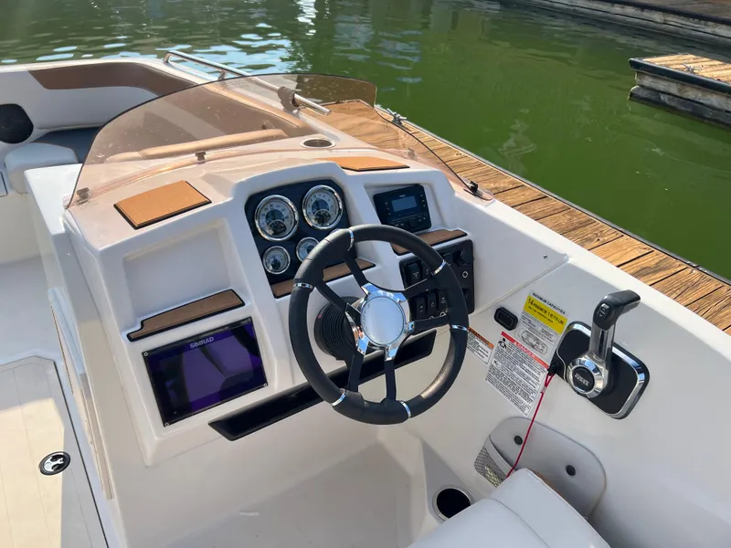 Slide: The Image of 2025 Starcraft SVX 231 IO boat dashboard with steering wheel and controls by the water. - 7