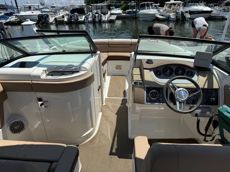 Slide: The Image of 2015 Sea Ray 270 Sundeck Outboard interior with helm, seating, and marina view. - 4