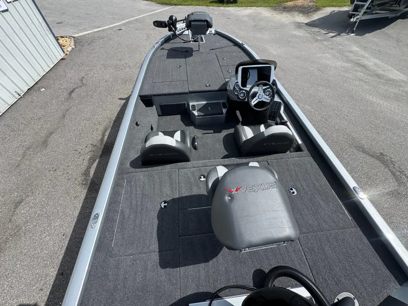 Slide: The Image of 2026 Vexus AVX1880 boat interior with steering console and seating, parked on pavement. - 10