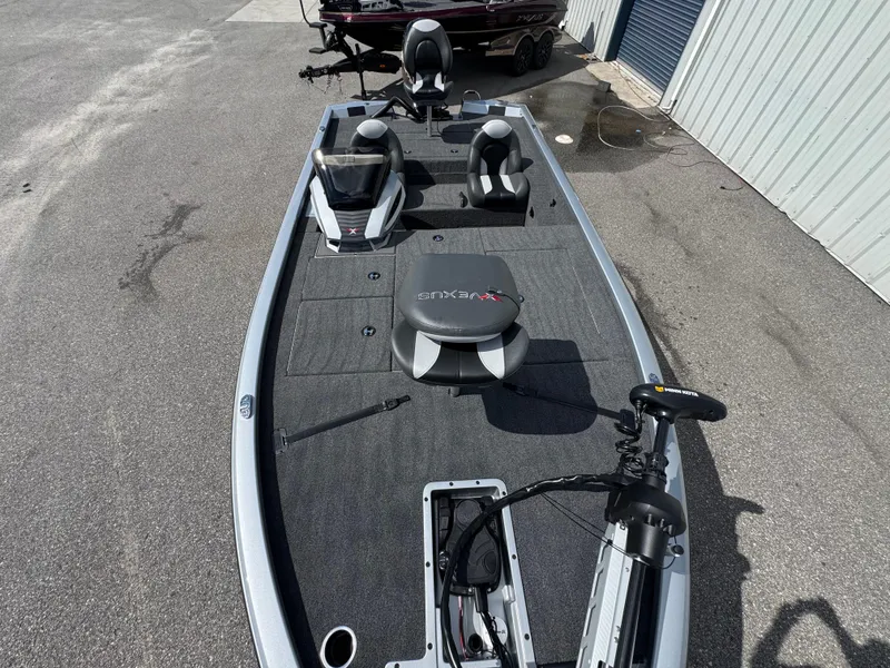 Slide: The Image of 2026 Vexus AVX1880 boat with seating and trolling motor, parked on pavement. - 8