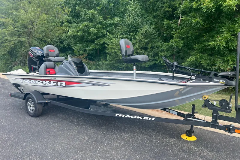 Slide: The Image of 2025 Tracker Pro Team 190 boat on trailer, parked near lush greenery. - 2