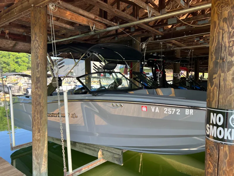 Slide: The Image of 2025 MasterCraft NXT23 boat docked in a wooden boathouse. - 2