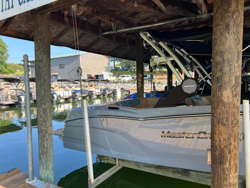 Slide: The Image of 2025 MasterCraft NXT23 boat docked in a marina under a wooden shelter. - 3