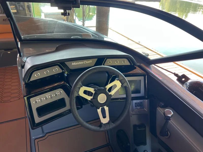 Slide: The Image of Interior dashboard of a 2025 MasterCraft NXT23 boat with steering wheel and controls. - 6