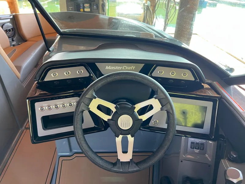 Slide: The Image of 2025 MasterCraft NXT23 boat dashboard with steering wheel and control panel. - 7