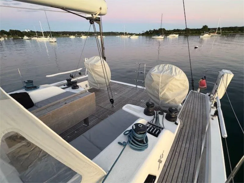 Slide: The Image of 2018 X-Yachts X4.9 sailboat deck with winches, moored in calm waters at sunset. - 24