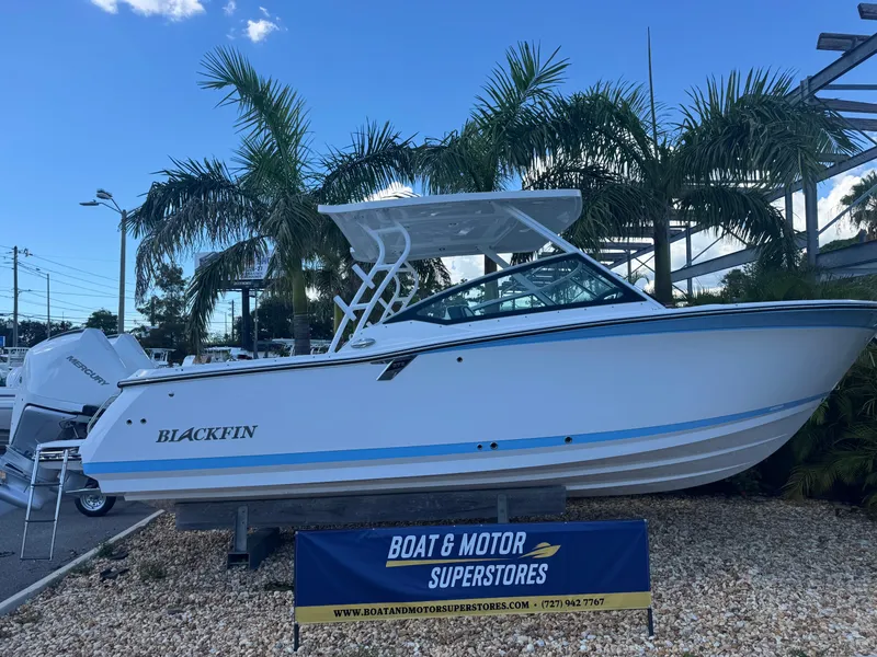 The Image of 2026 Blackfin 272 DC boat displayed at dealership with palm trees in background. - 1