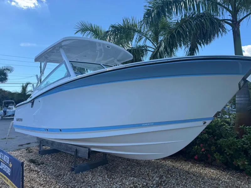 Slide: The Image of 2026 Blackfin 272 DC boat displayed outdoors with palm trees in the background. - 2