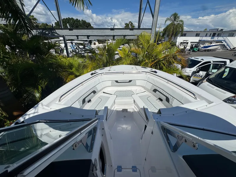 Slide: The Image of 2026 Blackfin 272 DC boat interior with white seating, surrounded by tropical plants. - 32
